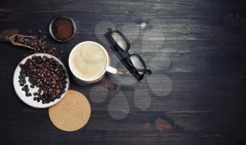 Still life with coffee cup, coffee beans, ground powder, beer coaster and glasses on vintage wooden background. Lot of copy space for your text. Top view. Flat lay.