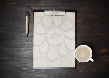 Stationery and coffee. Clipboard with kraft paper letterhead, coffee with milk cup and pen on wood table background. Copy space for your text. Flat lay.