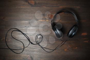 Black stereo headphones on wooden background. Flat lay.