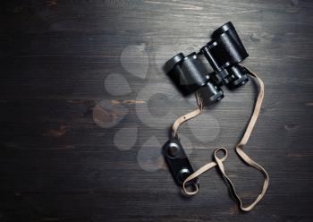 Photo of black vintage binocular on wooden background. Top view. Flat lay.