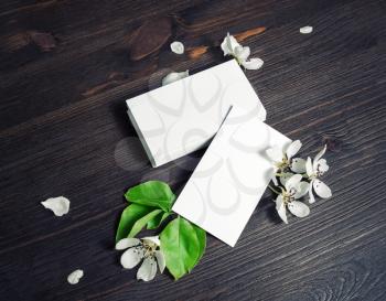 Photo of blank white business cards and flowers on wooden background. Branding ID template.