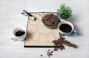 Clipboard with kraft letterhead, coffee cups, coffee beans, glasses and plant.