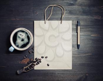 Photo of blank kraft paper bag, coffee cup, roasted coffee beans and pen on vintage wood table background. Top view. Flat lay.