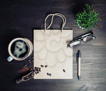 Still life with kraft paper bag, coffee cup, coffee beans, glasses, pen and plant on vintage wood table background. Flat lay.
