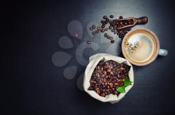 Hot coffee cup and coffee beans on black kitchen table background. Lot of copy space for your text. Top view. Flat lay.