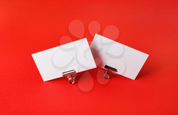 Photo of two blank business cards on red paper background. Branding ID template.