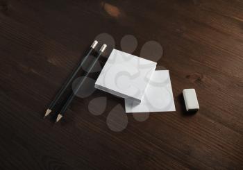 White square notes, pencils and eraser on wooden background. Blank stationery template.