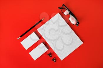 Blank stationery template on red paper background. Mock-up for branding identity. For design presentations and portfolios. Top view. Flat lay.