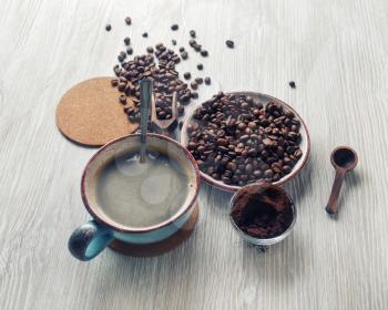 Fresh delicious coffee. Coffee cup, roasted coffee beans and ground powder on wooden background.