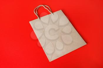 Blank kraft paper bag on red paper background. Recyclable package. Template ready for your design.