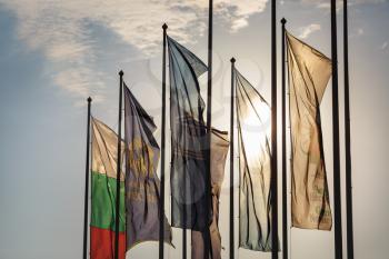 Nesebar, Bulgaria - September 10, 2014: Vertical flags on flagpoles on a sunset background.