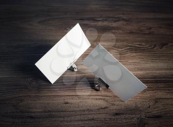 Photo of blank business cards and metal binder clips on wooden background.