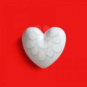 White styrofoam heart on red background. Top view. Flat lay.
