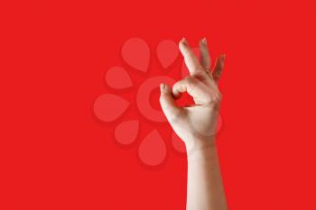 Hand ok sign. Female hand shows gesture OK over red background.