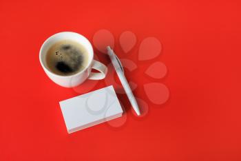 Photo of blank business cards, coffee cup and pen on red paper background. Corporate identity template.
