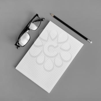 Blank copybook, pencil and glasses on gray paper background. Responsive design mockup. Top view. Flat lay.