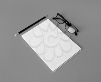 Photo of blank copybook, glasses and pencil on gray paper background. Copy space for text.