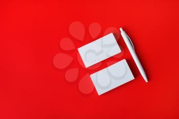 Blank business cards and pen on red paper background.Top view. Flat lay.