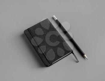 Blank black notepad and pencil on gray paper background. Template for branding design.