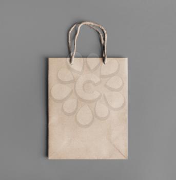 Blank craft paper bag on gray paper background. Responsive design mockup. Flat lay.