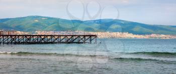 Old rusty pier, mountains and sea. Beautiful seascape. Panoramic shot.
