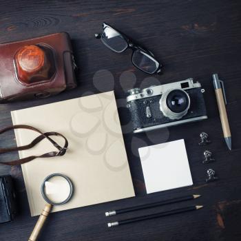 Vintage travel items. Blank stationery and retro camera on wood table background. Flat lay.