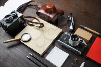 Planning vacation trip with retro camera and vintage stationery on wooden background.