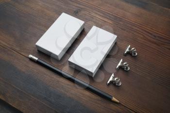 Blank business cards, pencil and paper clips on wooden background. Stationery mock up.