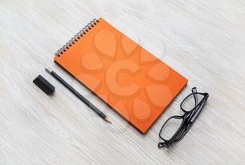 Black notepad, glasses, pencil and eraser on light wood table background. Copy space for your text.