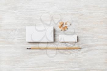 Blank business card, pencil and eraser on light wooden background. Stationery mockup. Objects for placing your design. Top view. Flat lay.