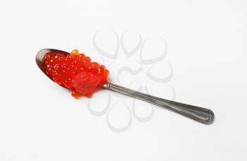 Red caviar in spoon on white table background.