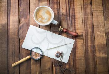 Photo of blank retro stationery and coffee cup on wooden background. Branding mock up. Flat lay.