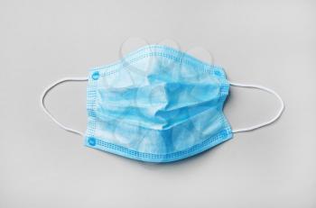 Blue medical face mask on paper background. Flat lay.