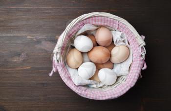Basket with eggs on wood table background. Flat lay.