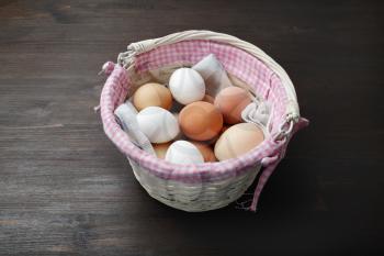 Eggs in wicker basket on wooden table.
