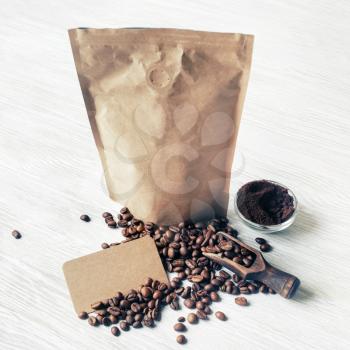 Still life with coffee beans, kraft paper package, ground powder and vintage business cards.