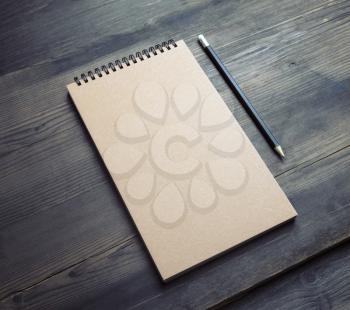 Photo of blank kraft notepad and pencil on wooden background. Responsive design template.