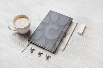 Photo of blank sketchbookk, pencil, eraser and coffee cup on light wood table background. Stationery mock up.