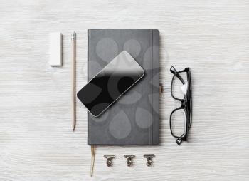 Blank business stationery set. Notebook, smartphone, glasses, pencil and eraser on light wood table background. Flat lay.