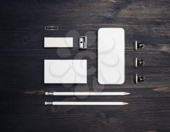 Smartphone and stationery: blank business card, pencils, eraser and sharpener on wood table background. Flat lay.