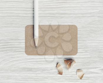 Photo of blank kraft business card and pencil on light wood table background. Blank stationery template. Top view. Flat lay.