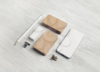 Blank stationery template on light wood table background. Kraft business cards, smartphone, pencil and eraser.