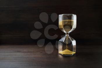 Hourglass on dark wooden background. Time concept.