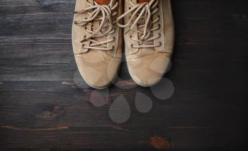 Sand-colored boots on brown wooden background. Flat lay.