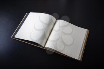 Blank open book on black paper background.