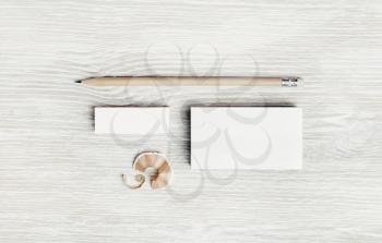 Blank white business card, pencil and eraser on light wood table background. Stationery mock up. Flat lay.
