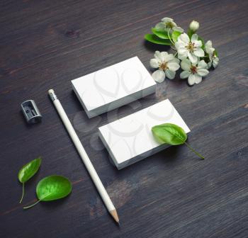 Blank white business cards mockup, pencil, sharpener and spring flowers on wood table background. Blank branding mockup.