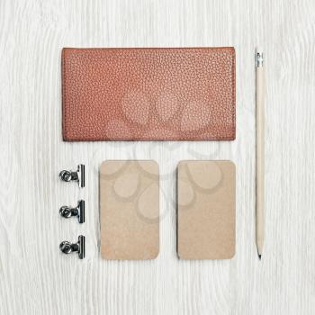 Photo of blank vintage stationery set on light wooden background. Notepad, kraft business cards and pencil. Flat lay.