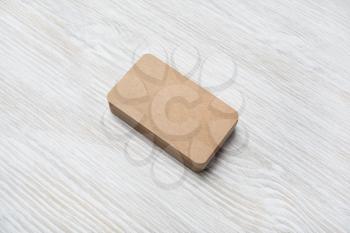 Photo of blank kraft business card on light wood table background. Mock-up for branding identity.