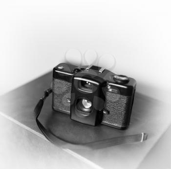 Black and white vintage camera with strap vignette bokeh background